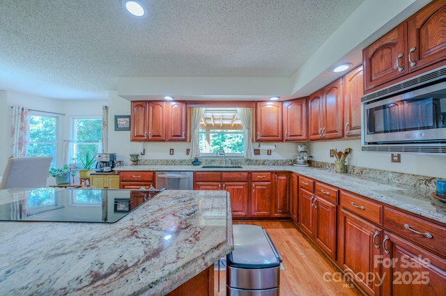 74 Challedon Dr, Candler, NC 28715 - kitchen with stainless steel appliances, a textured ceiling, light stone countertops, healthy amount of natural light, and brown cabinetry