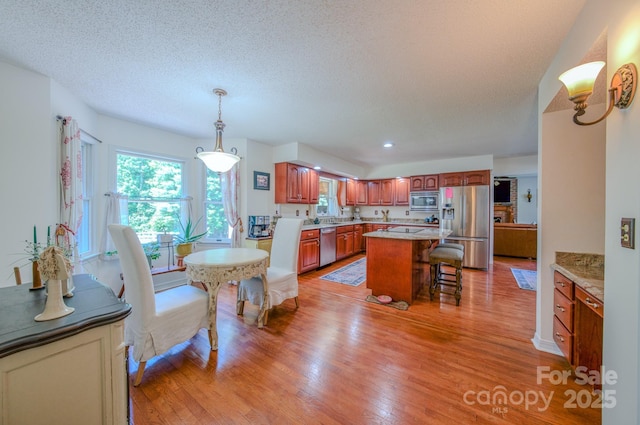 74 Challedon Dr, Candler, NC 28715 - kitchen with appliances with stainless steel finishes, light wood-style flooring, a breakfast bar, a center island, and a textured ceiling