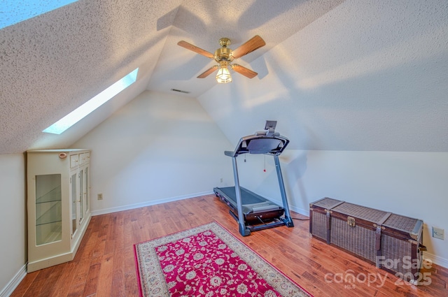 74 Challedon Dr, Candler, NC 28715 - exercise room featuring a skylight, wood finished floors, vaulted ceiling, a textured ceiling, and a ceiling fan