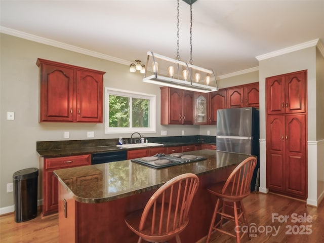 6620 Amos Smith Rd, Charlotte, NC 28214 - kitchen with dark brown cabinets, wood finished floors, a center island, freestanding refrigerator, and dishwasher