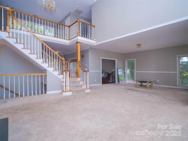 6620 Amos Smith Rd, Charlotte, NC 28214 - unfurnished living room featuring a high ceiling, carpet flooring, plenty of natural light, and stairs