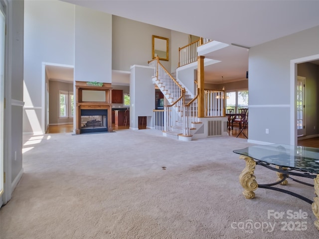 6620 Amos Smith Rd, Charlotte, NC 28214 - unfurnished living room featuring a high ceiling, stairway, plenty of natural light, carpet, and a multi sided fireplace