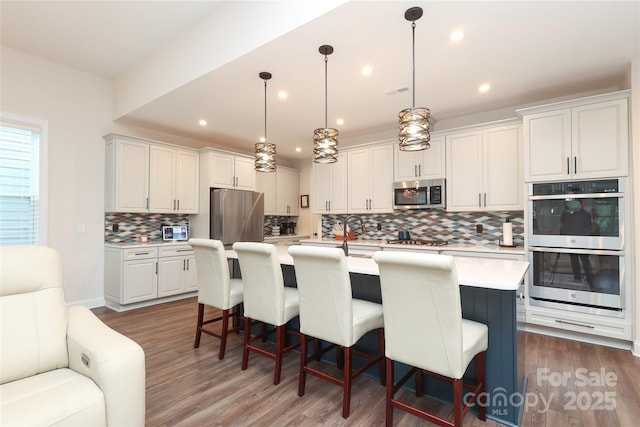 10240 Superb Ln, Charlotte, NC 28215 - kitchen with appliances with stainless steel finishes, decorative backsplash, light countertops, wood finished floors, and a breakfast bar