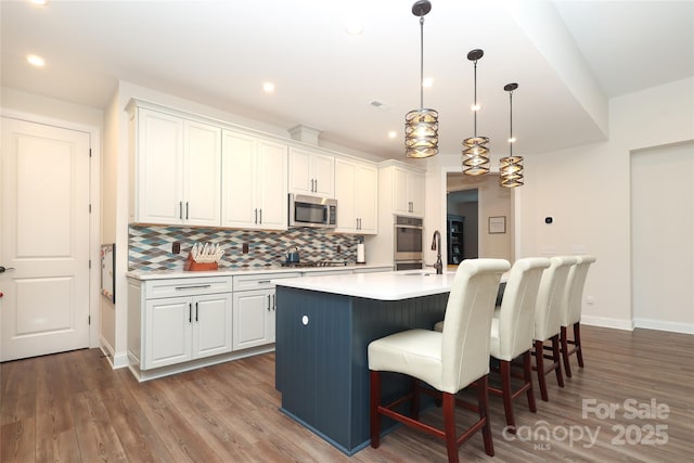 10240 Superb Ln, Charlotte, NC 28215 - kitchen featuring appliances with stainless steel finishes, light countertops, tasteful backsplash, a breakfast bar, and wood finished floors