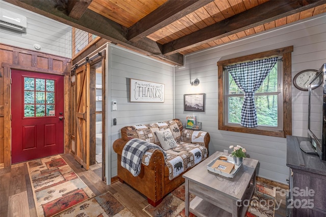 477 Locust Dr, Maggie Valley, NC 28751 - living room with a barn door, wooden walls, a wood ceiling with exposed beams, a wall mounted air conditioner, and hardwood / wood-style flooring