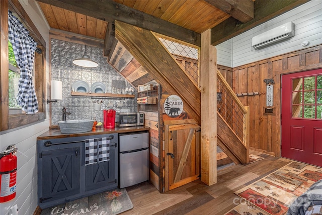 477 Locust Dr, Maggie Valley, NC 28751 - kitchen featuring appliances with stainless steel finishes, an AC wall unit, dark countertops, wood finished floors, and wooden walls