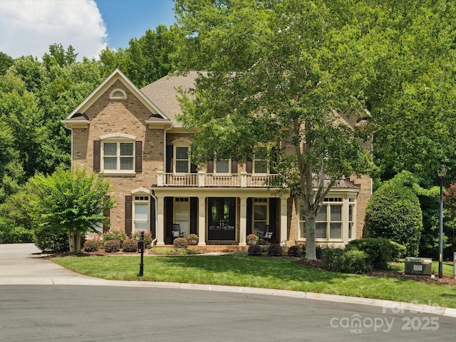 2103 Lytton Ln, Matthews, NC 28104 - colonial house with a balcony, brick siding, a front lawn, and a porch