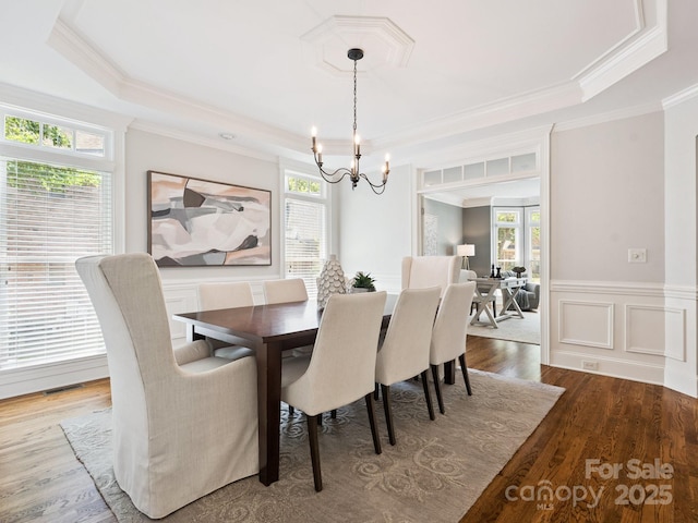2103 Lytton Ln, Matthews, NC 28104 - dining room with a raised ceiling, a chandelier, wood finished floors, ornamental molding, and wainscoting