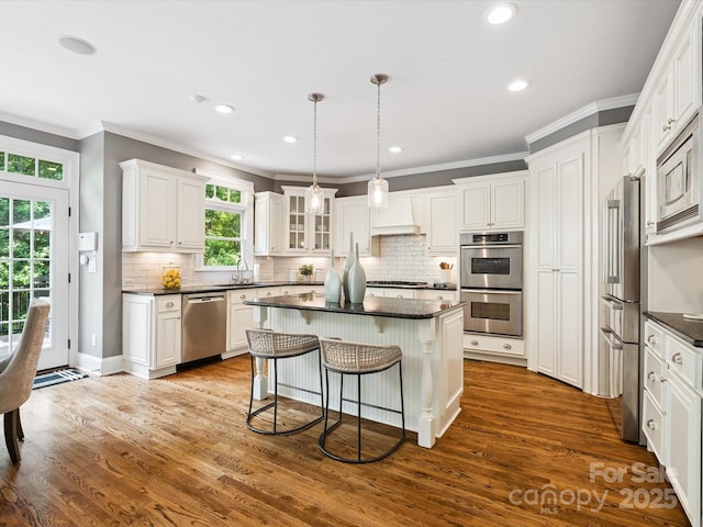 2103 Lytton Ln, Matthews, NC 28104 - kitchen with appliances with stainless steel finishes, dark countertops, a breakfast bar area, a kitchen island, and ornamental molding