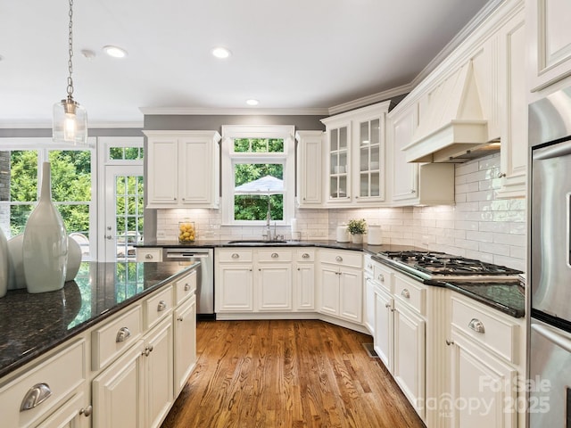 2103 Lytton Ln, Matthews, NC 28104 - kitchen featuring appliances with stainless steel finishes, crown molding, decorative light fixtures, light wood finished floors, and backsplash
