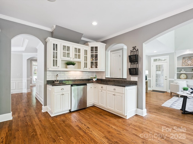 2103 Lytton Ln, Matthews, NC 28104 - kitchen featuring dishwasher, crown molding, dark countertops, light wood-type flooring, and glass insert cabinets