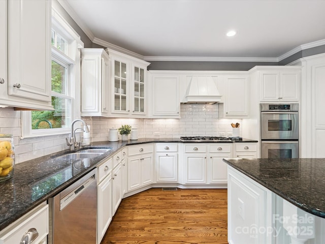 2103 Lytton Ln, Matthews, NC 28104 - kitchen with stainless steel appliances, white cabinets, premium range hood, light wood finished floors, and crown molding
