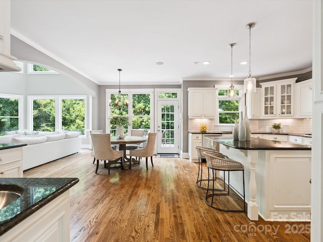 2103 Lytton Ln, Matthews, NC 28104 - kitchen featuring crown molding, a kitchen breakfast bar, white cabinets, decorative light fixtures, and backsplash
