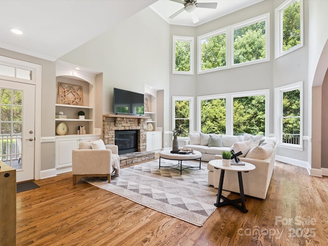 2103 Lytton Ln, Matthews, NC 28104 - living area featuring a ceiling fan, a towering ceiling, ornamental molding, wood finished floors, and a stone fireplace