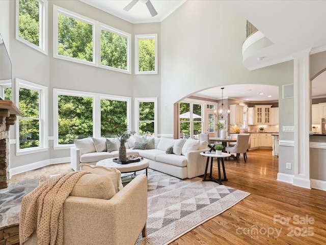 2103 Lytton Ln, Matthews, NC 28104 - living area with arched walkways, a towering ceiling, crown molding, a ceiling fan, and light wood-style floors