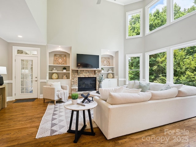 2103 Lytton Ln, Matthews, NC 28104 - living room with a towering ceiling, wood finished floors, a stone fireplace, built in features, and ornamental molding