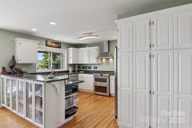 600 Summit Rdg Unit 34, Waynesville, NC 28786 - kitchen featuring wall chimney range hood, stainless steel appliances, white cabinets, a peninsula, and recessed lighting