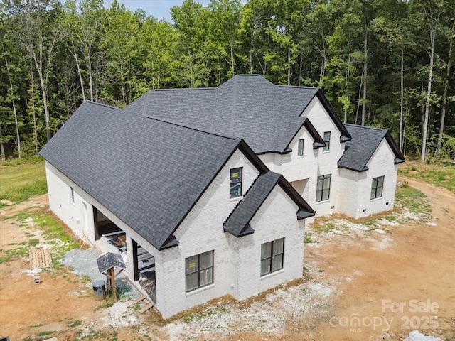 8018 Fairmont Dr, Waxhaw, NC 28173 - view of side of property with brick siding, a shingled roof, and a view of trees
