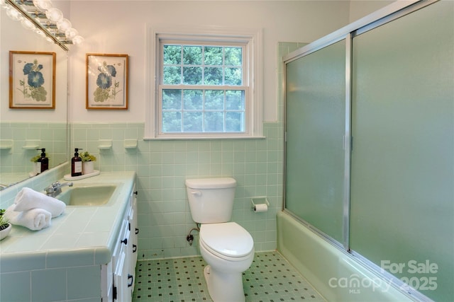 303 Odell St, Kannapolis, NC 28083 - bathroom with vanity, wainscoting, tile walls, and bath / shower combo with glass door