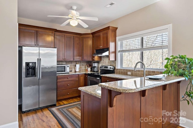 244 Timberlake Rd, Bostic, NC 28018 - kitchen featuring stainless steel appliances, under cabinet range hood, a peninsula, light stone counters, and tasteful backsplash