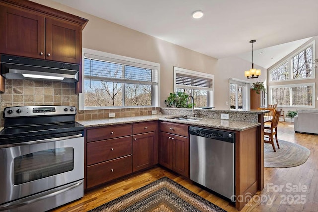 244 Timberlake Rd, Bostic, NC 28018 - kitchen with appliances with stainless steel finishes, under cabinet range hood, light wood-type flooring, a chandelier, and vaulted ceiling