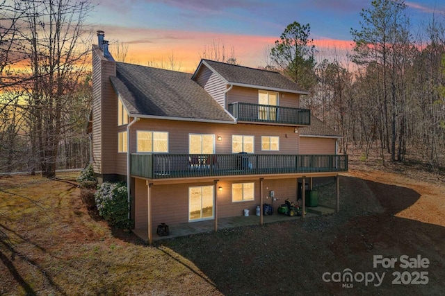 244 Timberlake Rd, Bostic, NC 28018 - back of house at dusk featuring a balcony, a chimney, a patio area, dirt driveway, and a wooden deck