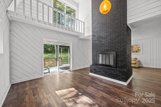 3276 Howard Gap Rd, Hendersonville, NC 28792 - unfurnished living room featuring a high ceiling, wood walls, wood finished floors, and a fireplace