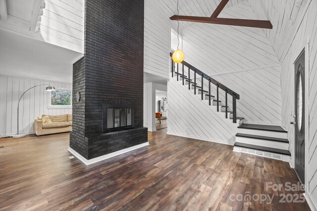 3276 Howard Gap Rd, Hendersonville, NC 28792 - unfurnished living room with a towering ceiling, wood finished floors, stairs, wooden walls, and a brick fireplace