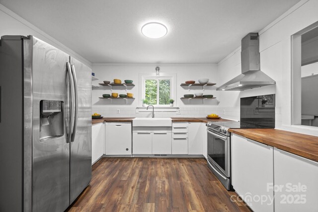 3276 Howard Gap Rd, Hendersonville, NC 28792 - kitchen featuring stainless steel appliances, wall chimney range hood, butcher block countertops, open shelves, and ornamental molding
