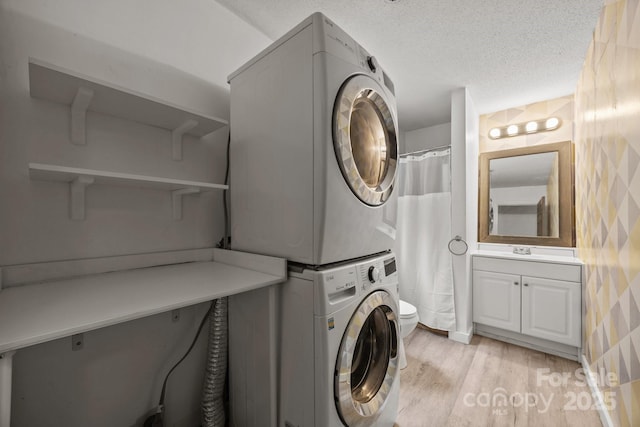 3276 Howard Gap Rd, Hendersonville, NC 28792 - laundry room featuring stacked washer / dryer, light wood-type flooring, and a textured ceiling