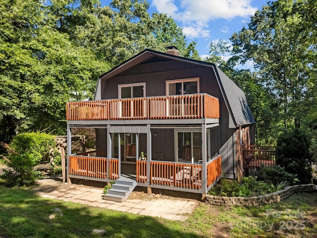 3276 Howard Gap Rd, Hendersonville, NC 28792 - back of house with a gambrel roof, a chimney, a wooden deck, and a balcony