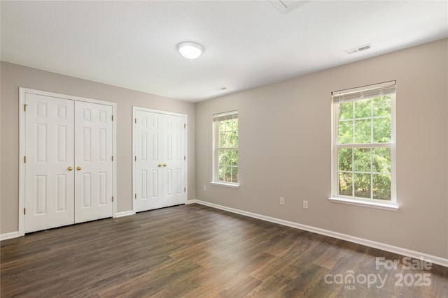256 Farington Cir Unit 128, Fletcher, NC 28732 - unfurnished bedroom featuring multiple closets and dark wood-style flooring