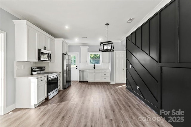405 E Broad St, Salisbury, NC 28144 - kitchen with appliances with stainless steel finishes, light wood-style flooring, light countertops, white cabinets, and ornamental molding