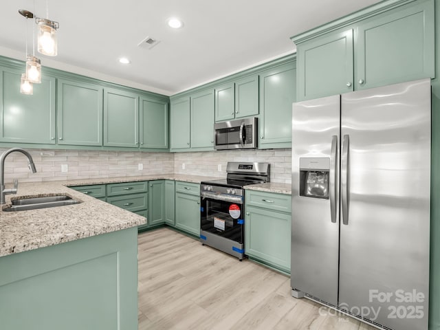 174 Charlie Randall Rd, Lawndale, NC 28090 - kitchen with appliances with stainless steel finishes, green cabinets, light wood-type flooring, decorative light fixtures, and light stone counters