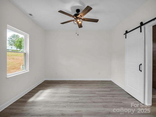 174 Charlie Randall Rd, Lawndale, NC 28090 - empty room featuring a barn door, a ceiling fan, and light wood-style floors