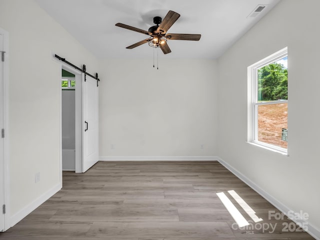 174 Charlie Randall Rd, Lawndale, NC 28090 - unfurnished bedroom featuring a barn door, multiple windows, light wood finished floors, and a ceiling fan