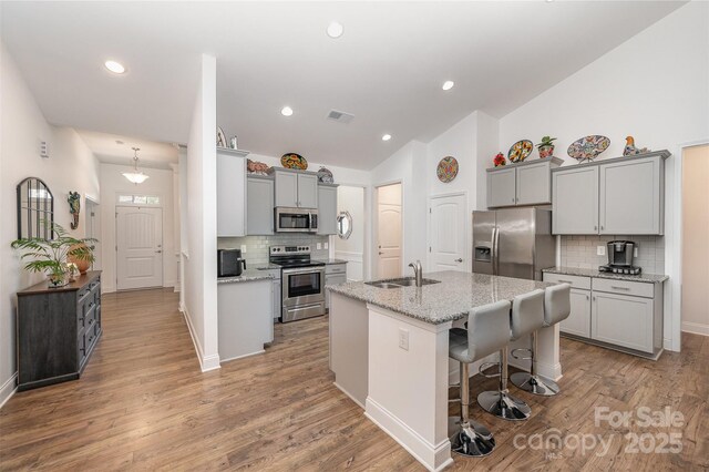 7718 Village Pkwy, Locust, NC 28097 - kitchen featuring stainless steel appliances, lofted ceiling, decorative backsplash, an island with sink, and gray cabinetry