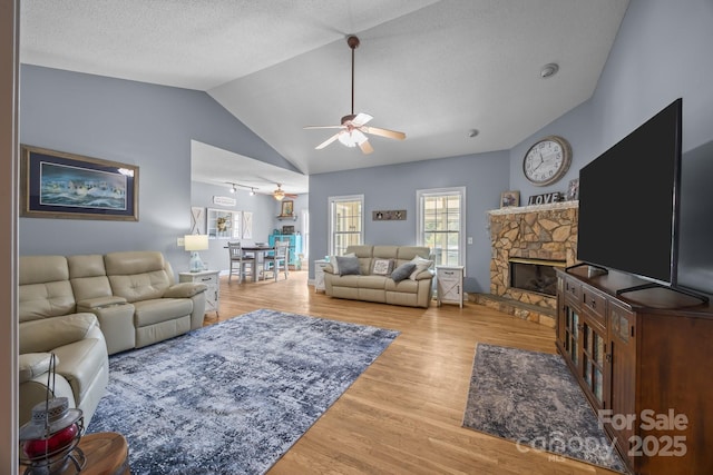 315 Talon Dr, Salisbury, NC 28147 - living room with ceiling fan, wood finished floors, a stone fireplace, vaulted ceiling, and a textured ceiling