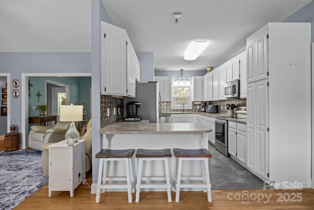 315 Talon Dr, Salisbury, NC 28147 - kitchen featuring stainless steel appliances, a peninsula, white cabinets, backsplash, and a breakfast bar