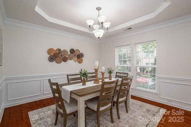 734 Naramore St, Davidson, NC 28036 - dining room with a chandelier, a raised ceiling, wood finished floors, wainscoting, and a decorative wall