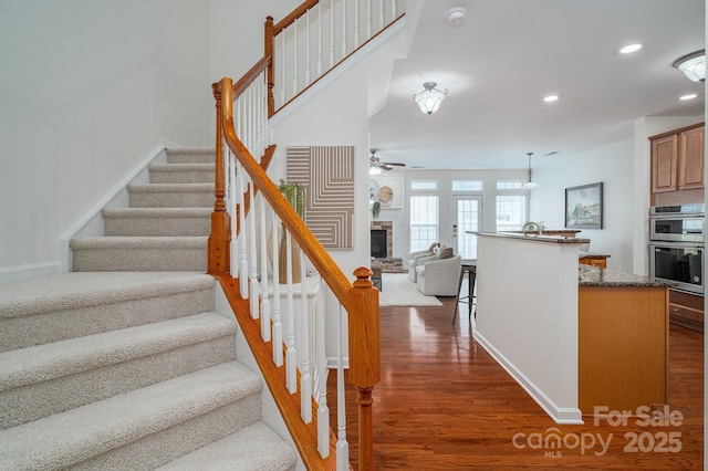734 Naramore St, Davidson, NC 28036 - stairway featuring wood finished floors, a fireplace, a ceiling fan, and recessed lighting