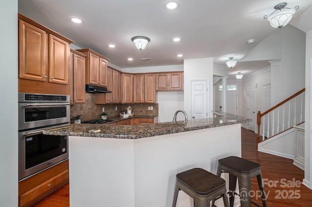 734 Naramore St, Davidson, NC 28036 - kitchen featuring stainless steel double oven, crown molding, ornate columns, tasteful backsplash, and dark wood-type flooring