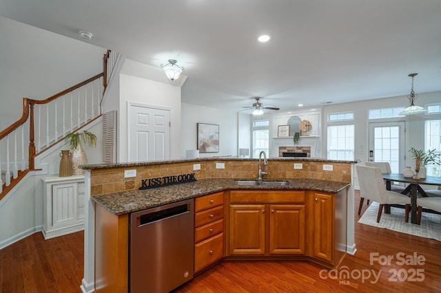 734 Naramore St, Davidson, NC 28036 - kitchen with stainless steel dishwasher, open floor plan, a ceiling fan, brown cabinets, and a fireplace