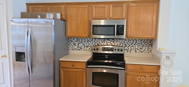 162 Autumn Falls Dr, Lake Wylie, SC 29710 - kitchen featuring stainless steel appliances, light countertops, backsplash, and brown cabinetry
