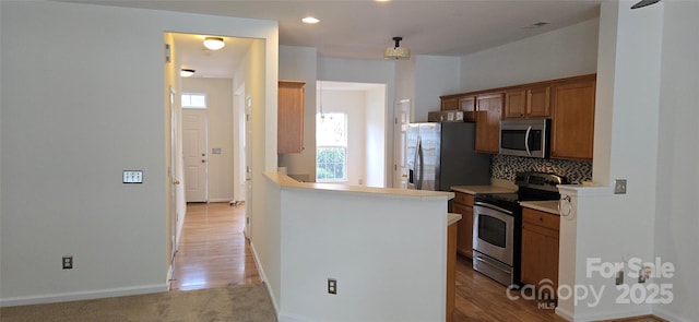 162 Autumn Falls Dr, Lake Wylie, SC 29710 - kitchen with stainless steel appliances, brown cabinets, tasteful backsplash, light countertops, and a peninsula