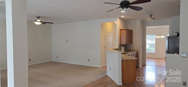 162 Autumn Falls Dr, Lake Wylie, SC 29710 - kitchen with freestanding refrigerator, ceiling fan, brown cabinetry, light wood-type flooring, and a chandelier