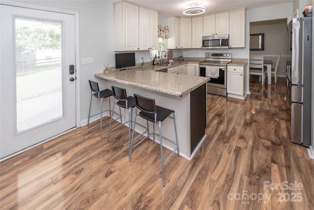 2085 Chapel Creek Rd SW, Concord, NC 28025 - kitchen featuring appliances with stainless steel finishes, a peninsula, white cabinets, and dark wood-type flooring