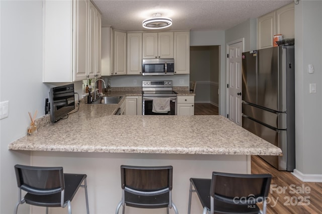 2085 Chapel Creek Rd SW, Concord, NC 28025 - kitchen featuring stainless steel appliances, a peninsula, light countertops, dark wood finished floors, and a textured ceiling