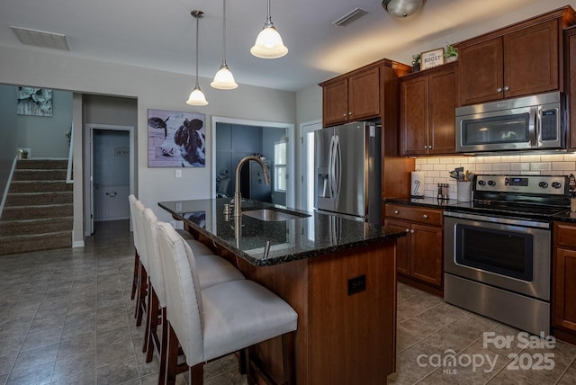 864 Pointe Andrews Dr, Concord, NC 28025 - kitchen with stainless steel appliances, backsplash, a kitchen breakfast bar, dark stone countertops, and an island with sink