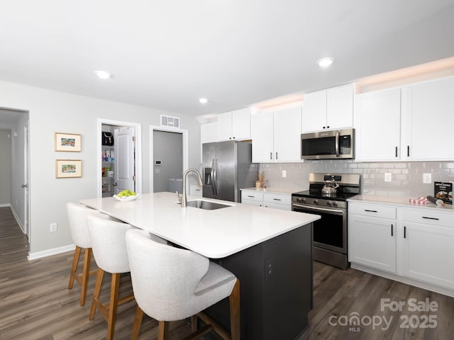 2796 Legacy Ridge Ln, Catawba, NC 28609 - kitchen with stainless steel appliances, decorative backsplash, a breakfast bar, an island with sink, and dark wood-style floors
